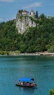 distant view of the castle on a stone cliff near the lake on a sunny day