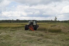 tractor mows grass among wetlands