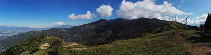 panorama of green mountains, windmills and white clouds