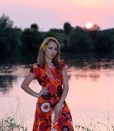 girl in a colorful dress near the lake at sunset