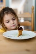 girl looks at half a muffin on a plate