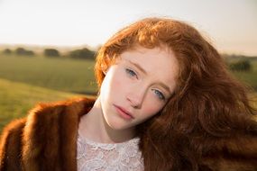 yound Girl with Red Hair and Blue Eyes in fur coat at Sunrise