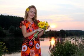 girl in a colorful dress with a bouquet of sunflowers at sunset
