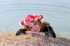 girl in a colorful wreath near the water