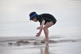 Toddler boy playing on the beach in the wet sand