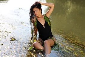 beautiful brunette in a black swimsuit posing in the water