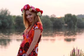 blonde in a colorful wreath near the water at sunset