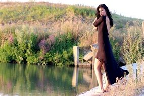 sensual brunette in a dark dress near the water