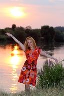 blonde in a colorful dress near the lake at sunset