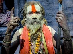 old bearded Hindu Man with painted body pointing up