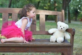 Girl with a teddy bear on a bench