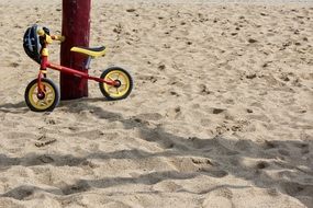 Children's bike stands near a pillar in the sand