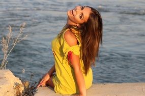 charming girl in a yellow dress posing near the water