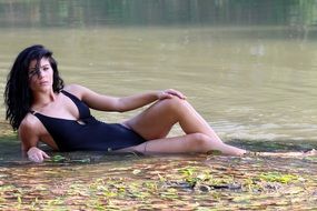 sensual brunette in a black swimsuit in the water