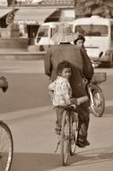 Child Girl on Bike at adult person’s back, Cambodia