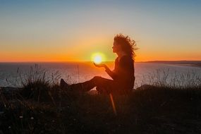 Silhouette of posing Girl on coast of Ocean at sunset