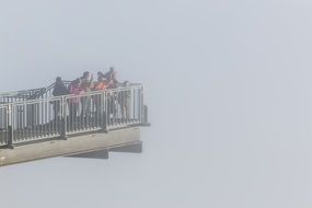 people on the observation deck over a large canyon in the fog
