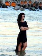 brunette in black dress standing in the water