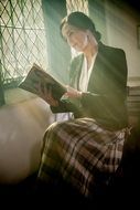 A woman is reading a book near the window