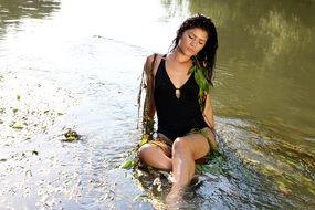 girl in a black bathing suit sits in the water