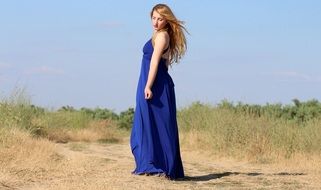 girl in long blue dress posing on a field