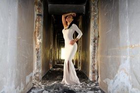 girl in a long white dress posing among the ruins