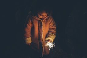 girl with sparkler in hand in the dark