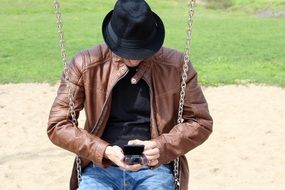 Man in Hat Sits on chain Swing