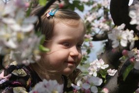 Child girl and colorful flowers on the tree in spring