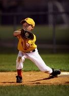 boy in yellow uniform stands on base during a baseball game