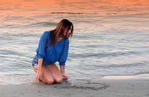 pretty woman drawing heart on the beach