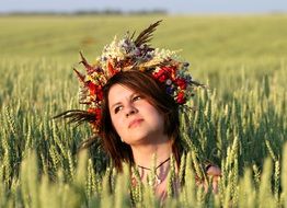 girl with a floral wreath on her head on the meadow