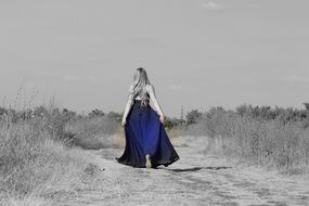girl in a long blue dress among nature in monochrome image