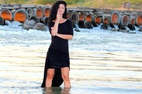 model in black dress standing in the water