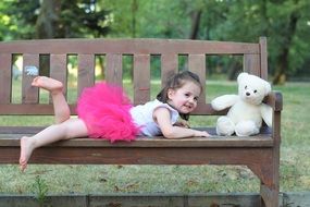 Girl on a bench next to a teddy bear