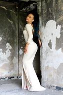 sensual brunette in a long white dress among the ruins