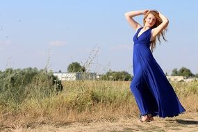 sensual girl in a long blue dress among nature