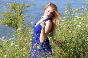 sensual girl in a long blue dress among tall grass