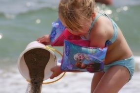 little girl plays with sand on the beach