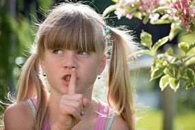girl with a finger at her lips on a blurred background
