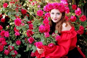 girl with rose wreath posing on the rose bush background