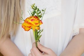 girl is standing with a flower in her hands