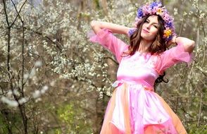woman in pink dress with floral wreath in the spring forest