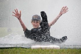child glides in the water on a soccer field