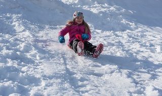 girl is sledding from the mountain