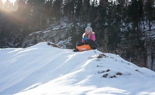 girl is sledding from a hill