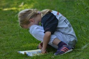 Child Reading A Magazine on a grass