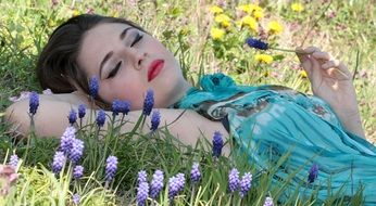 beautiful girl lies among flowers on the grass