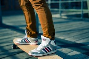 photo of legs of a young man in brown jeans and white sneakers