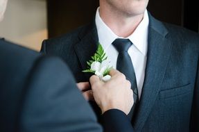 groom in a suit with a white flower